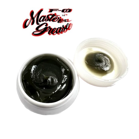 Abgebildet ist ein weißer ZPI F-Zero Master Grease | Rollenfett-Behälter mit dunklem Fett und offenem Deckel, auf dem Rückstände zu sehen sind, mit dem Master Grease-Logo darüber auf weißem Hintergrund.