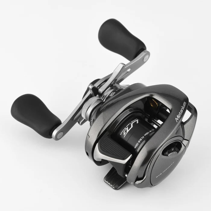 Die Gomexus Flat Spool BFS Spule Aluminium fΓΌr Shimano 20 & 22 Metanium ist eine schwarz-silberne Baitcasting-Rolle mit zwei ergonomischen Griffen, einem seitlichen Einstellknopf und sichtbaren BFS-Tuning-Komponenten, dargestellt auf einem schlichten weiΓen Hintergrund.