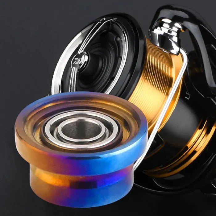 Nahaufnahme des Gomexus Schnurlaufröllchens für Daiwa 23 Regalis von Gomexus mit einer Metallspule mit blauem, goldenem und orangefarbenem Farbverlauf und sichtbarem Kugellager auf schwarzem Hintergrund.