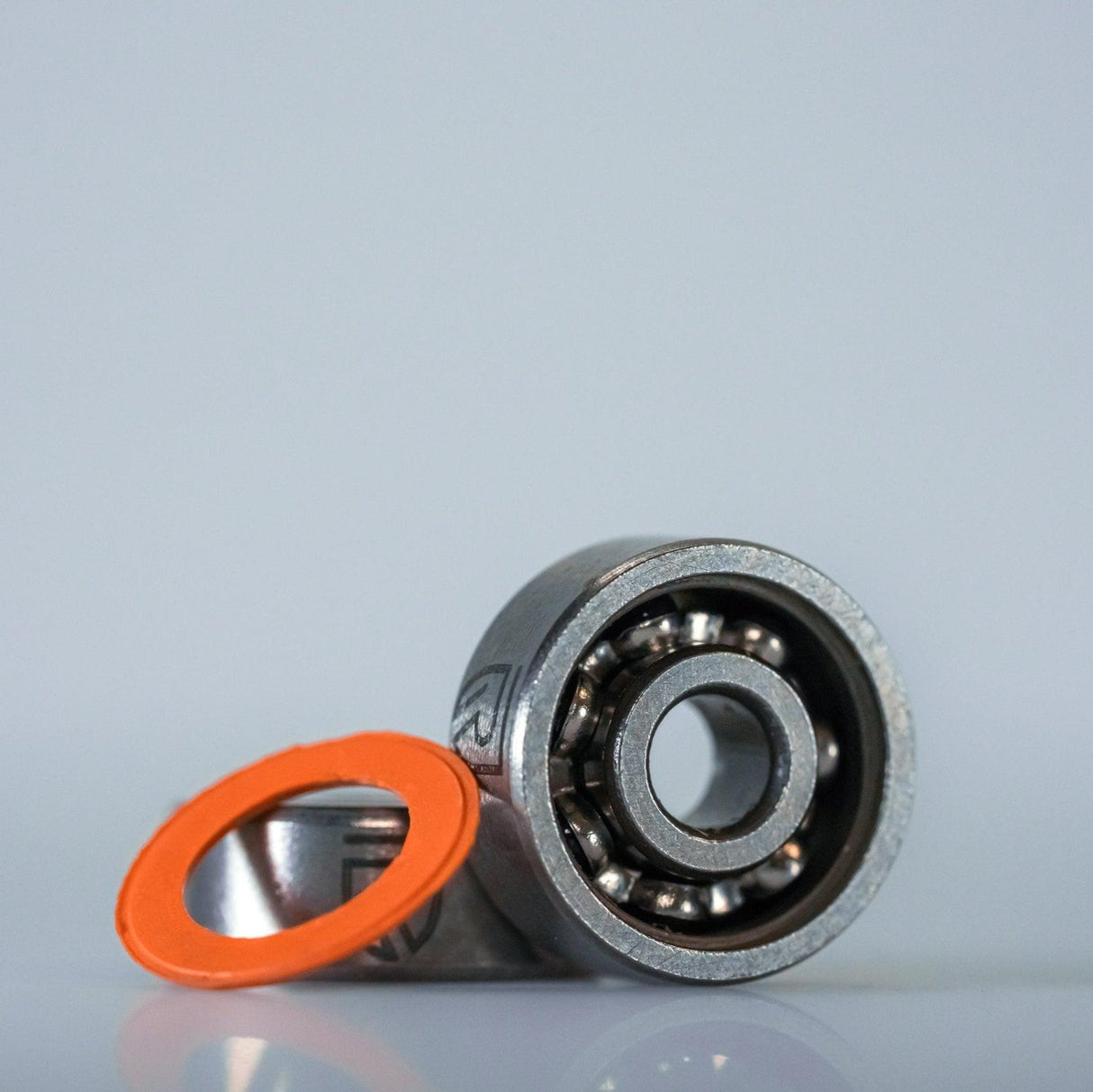 Das RL-TNG Hybrid Keramik Kugellager (ABEC 9) von RL-Angelrollentuning ist mit entfernter orangefarbener Gummidichtung abgebildet, ideal fΓΌr das Tuning von Baitcaster-Angelrollen, auf einem schlichten hellgrauen Hintergrund.