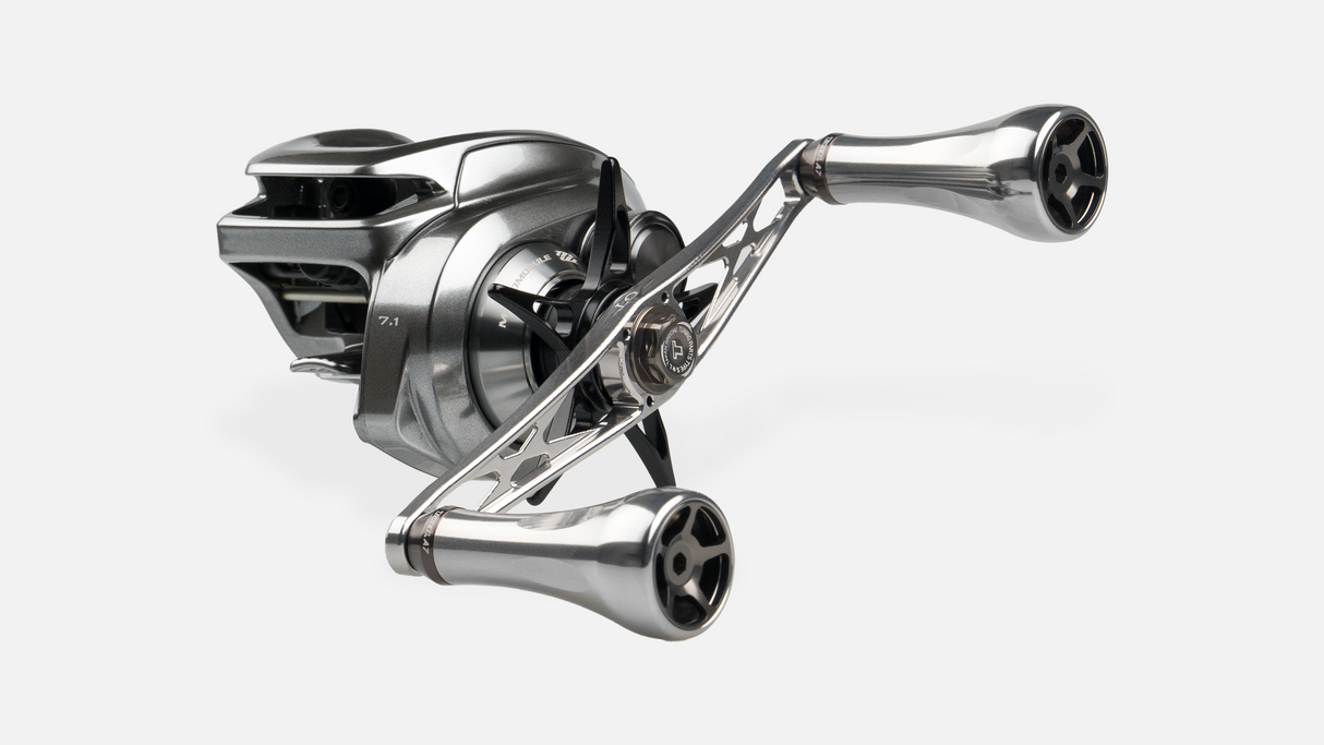 Der Taken GT106 Griff von Taken ist ein Griff aus Duraluminium mit A7 AluminiumknΓΆpfen fΓΌr Shimano und Daiwa. Er ist in Silber mit einer groΓen Spule und einem Metallrahmen vor einem schlichten weiΓen Hintergrund dargestellt.