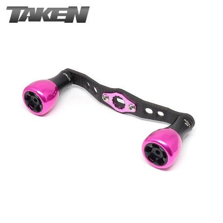 Der Taken H7 SS Crossover Carbon Handle 100 mm - Carbon Power Handle mit H7 Aluminium Knobs in Rosa für Shimano & Daiwa ist mit schwarzen Akzenten und dem TAKEN Logo in der linken oberen Ecke auf weißem Hintergrund abgebildet.