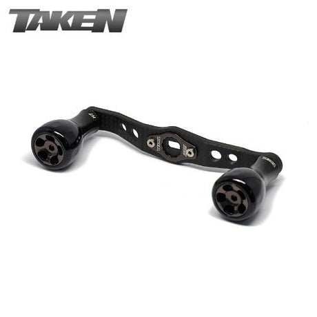 Ein Taken H7 SS Crossover Carbon Griff 100 mm in Schwarz, mit H7 Aluminium Knobs für Shimano & Daiwa, und TAKEN Logo oben links auf weißem Hintergrund.
