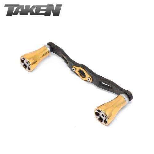 Der Taken One11 A2 Carbon Griff 111 mm von Taken verfügt über goldene A2 Aluminiumknöpfe für Shimano & Daiwa Rollen, abgebildet auf weißem Hintergrund mit dem TAKEN Logo in der oberen linken Ecke.