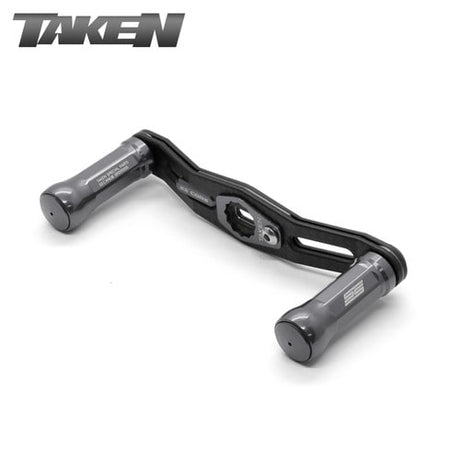 Eine gunmetalfarbene Taken SS Carbon Handle 90 mm Tuning-Doppelrahmen-Carbonkurbel mit SS-Aluminiumknöpfen für Shimano & Daiwa wird vor einem weißen Hintergrund gezeigt; die Marke Taken erscheint oben links, ideal für Fans des Finesse-Fischens.