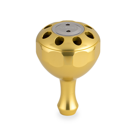 Der Taken X3 Knob 50mm von Taken ist ein goldfarbener, metallischer Power-Tuning-Knopf für Shimano- und Daiwa-Rollen. Er verfügt über eine runde, belüftete Oberseite mit mehreren Löchern und einer zentralen silbernen Scheibe sowie einem kurzen, konischen Schaft. Ideal für das Hecht- und Bigbait-Angeln.