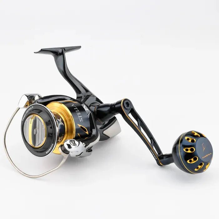 Der Gomexus Aluminium Reel Power Knob 45-47 mm Typ B von Gomexus ist in Schwarz und Gold mit metallischen Akzenten gehalten und zeigt einen großen Aluminiumgriff mit Power Knob, eine eingebrannte Spule und einen Ballenarm auf einem weißen Hintergrund.