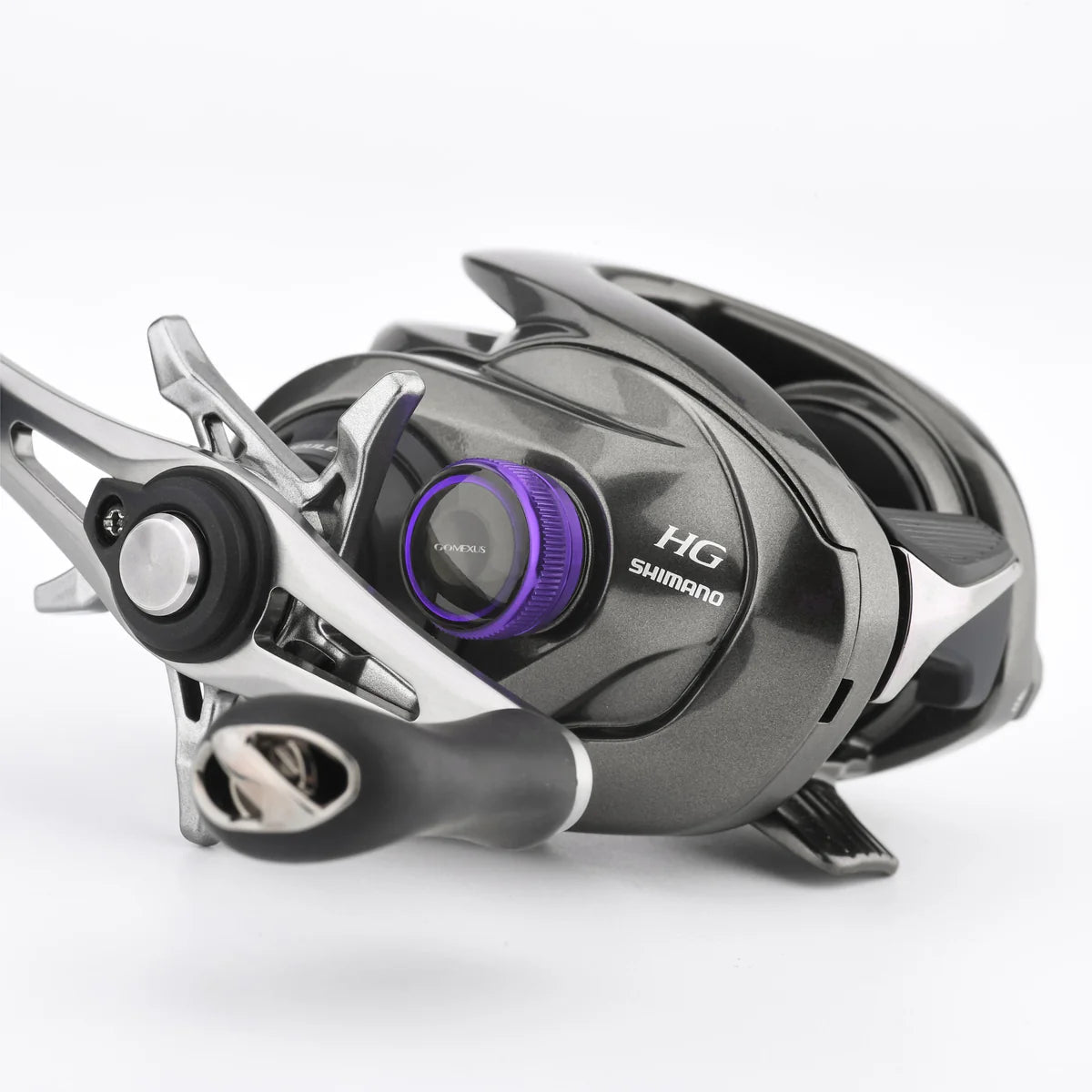 Eine Nahaufnahme einer Shimano Baitcaster HG-Rolle mit Metallic-Lackierung, schwarzem Griff und einer Gomexus Aluminium-Spulenspannungsknopfkappe für 20/22/23 Metanium, wobei alle Markenzeichen auf einem schlichten weißen Hintergrund sichtbar sind.