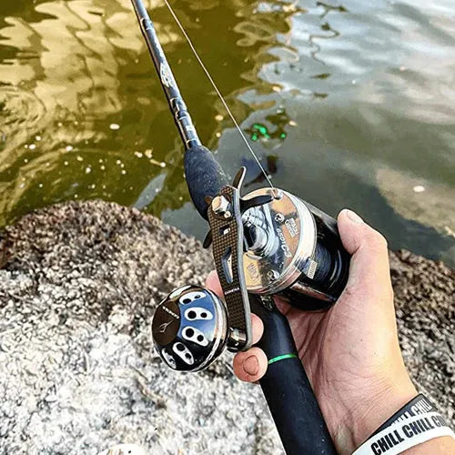 Eine Person greift einen Gomexus Carbon Handle 75 mm mit 38 mm Power Knob (8x5mm), steht über Felsen in trübem Wasser und trägt ein "CHILL CHILL"-Armband.