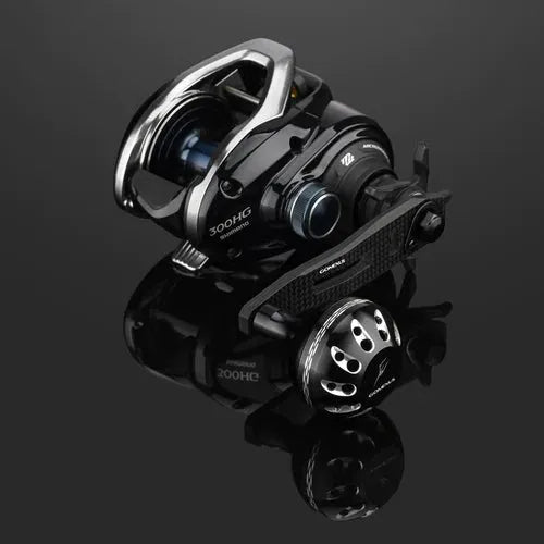 Der Gomexus Carbon Handle 75 mm mit 38 mm Power Knob (8x5mm) im eleganten schwarz-silbernen Design, Edelstahl Kugellager und Karbonkurbel wird auf einer reflektierenden Oberfläche ausgestellt, um die detaillierten Metallkomponenten zu präsentieren.