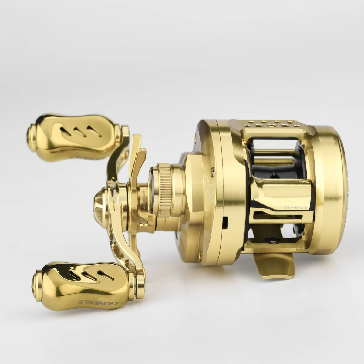 Eine Gomexus-Kupplung für 21-22 Calcutta Conquest und 23 Calcutta Conquest BFS ist auf weißem Hintergrund abgebildet, wobei das goldene Finish und die Einstellknöpfe zur Geltung kommen - perfekt für Liebhaber des Baitcaster-Tunings.