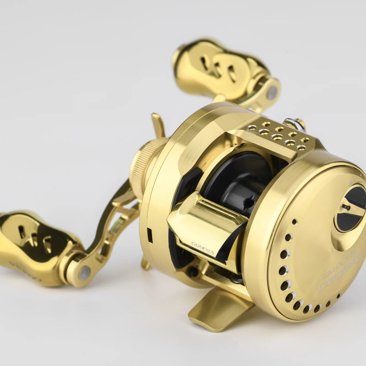 Die Gomexus Clutch für die 21-22 Calcutta Conquest und die 23 Calcutta Conquest BFS ist ein goldfarbenes Teil für Baitcasting-Rollen mit zwei Griffen, einem Sternwiderstand und einer Spule - ideal für das Baitcaster-Tuning - auf einem schlichten hellen Hintergrund.