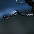 Eine Nahaufnahme des Gomexus CraftFin-35 Carbongriffs für Stationärrollen, mit einem 35mm Carbon-Kurbelarm und einem 18mm-Knauf für ultraleichte Angelrollen, angebracht an einer Rolle vor einem unscharfen dunklen Hintergrund.