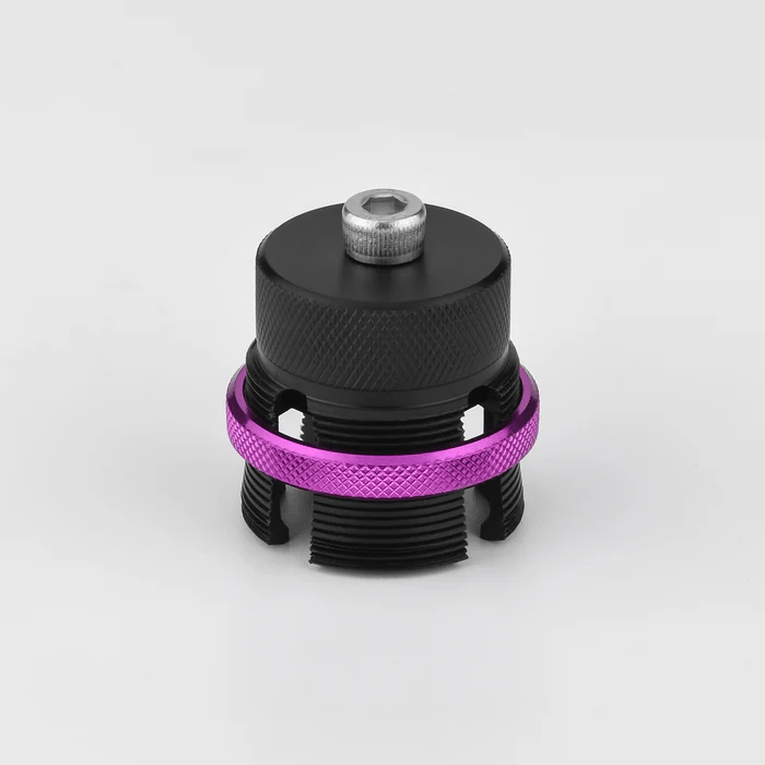 Die Gomexus Flat Spool für Shimano 20 & 22 Metanium, eine schwarze Aluminium-BFS-Spule mit einem gerändelten lila Ring und einem silbernen Bolzen, wird vor einem schlichten weißen Hintergrund gezeigt.