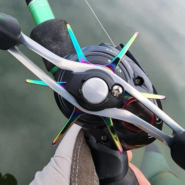 Eine behandschuhte Hand hält eine Shimano-Angelrolle mit dem bunten Metallgriff der Gomexus Sternbremse 60 mm über Wasser.