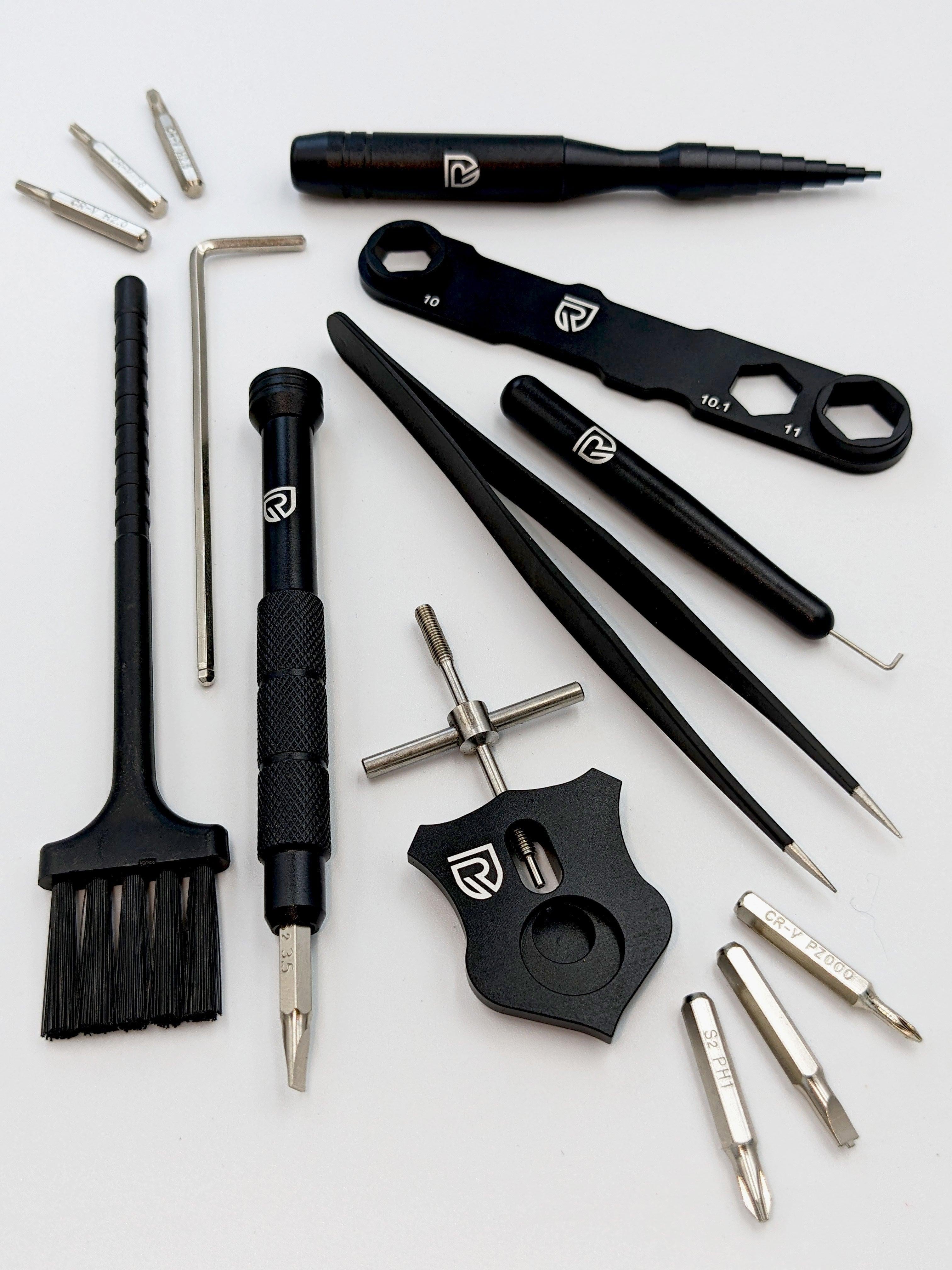 Das RL-Angelrollentuning Ready to Go Wartungskit bietet schwarz-silberne Präzisionswerkzeuge – Schraubendreher, Pinzette, Bürste, Inbusschlüssel, Schraubenschlüssel und Metallbits – übersichtlich angeordnet für die Baitcaster-Pflege.
