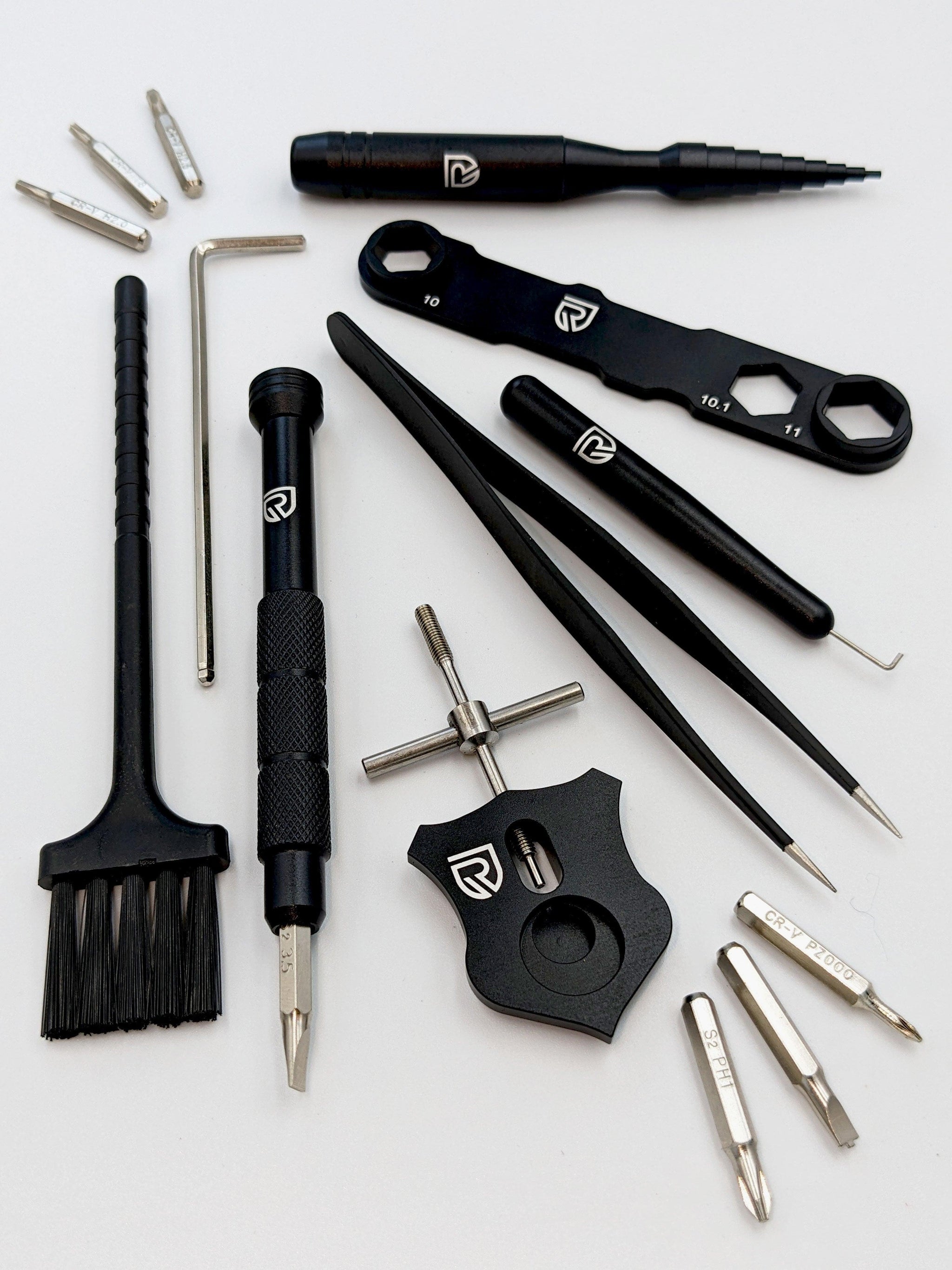 Das RL-Angelrollentuning Ready to Go Wartungskit bietet schwarz-silberne Präzisionswerkzeuge – Schraubendreher, Pinzette, Bürste, Inbusschlüssel, Schraubenschlüssel und Metallbits – übersichtlich angeordnet für die Baitcaster-Pflege.