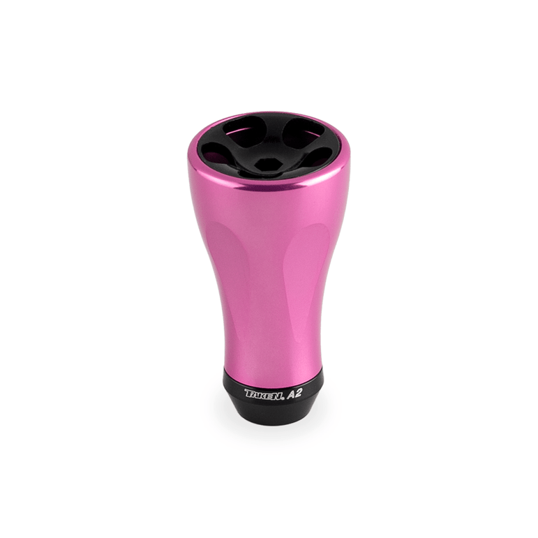 Ein Taken A2 Knauf 36mm Tuning Aluminium Knauf für Shimano & Daiwa Rollen von Taken, in rosa, mit einer schwarzen Oberseite mit vier Löchern und einer schwarzen Basis mit der Aufschrift THRILL A2, auf weißem Hintergrund.