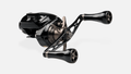 Der Taken GT106 Handle von Taken ist ein schwarzer Power Handle aus Duraluminium mit zwei großen A7 Aluminiumknöpfen für Shimano & Daiwa, abgebildet auf einer schlanken kompakten Rolle vor einem schlichten weißen Hintergrund.