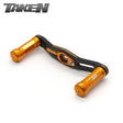 Der Taken SS Carbon Handle 90mm verfügt über orangefarbene SS-Aluminiumknöpfe und einen Carbonrahmen, der mit Shimano- und Daiwa-Rollen kompatibel ist - ideal für Finesse und ultraleichte Baitcaster-Setups. Mit dem Taken-Logo auf weißem Hintergrund dargestellt.