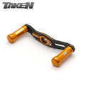 Der Taken SS Carbon Handle 90mm verfügt über orangefarbene SS-Aluminiumknöpfe und einen Carbonrahmen, der mit Shimano- und Daiwa-Rollen kompatibel ist - ideal für Finesse und ultraleichte Baitcaster-Setups. Mit dem Taken-Logo auf weißem Hintergrund dargestellt.