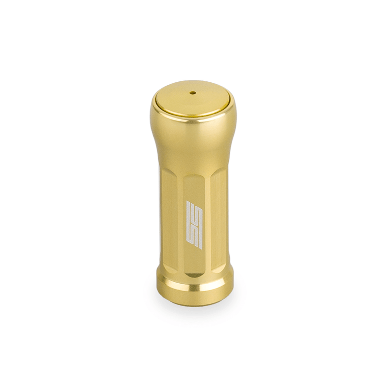 Der Taken SS Knob 35mm ist ein weicher, goldfarbener Aluminium-Stimmknopf für Shimano- und Daiwa-Rollen. Er verfügt über eine flache Oberseite mit zentralem Loch, seitlichen Rillen und einem weißen Logo - perfekt als Upgrade Baitcaster Rollen Knob. Abgebildet auf einem weißen Hintergrund.