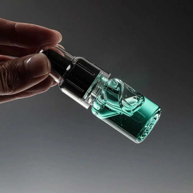 Eine Hand hält eine kleine Tropfflasche aus Glas mit Glitch Oil High Spec Bearing von Glitch Oil Japan, gefüllt mit transparenter blaugrüner Flüssigkeit und mit einer schwarzen Tropfkappe, vor einem dunklen Hintergrund mit Farbverlauf, von der Seite gezeigt.