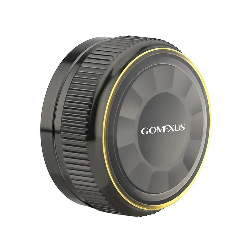 Auf weißem Hintergrund ist eine schwarze, runde Gomexus Aluminium-Spulenspannungsknopfkappe für 20/22/23 Metanium aus einer Aluminiumlegierung mit strukturiertem Griff und dünnem gelben Akzentring abgebildet.