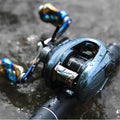 Eine Nahaufnahme einer blauen Gomexus Aluminiumspule für Shimano 22 Aldebaran BFS mit Wassertropfen auf der Oberfläche liegt auf nassen Felsen. Der mehrfarbige Griff und die Rute betonen das Bait Finesse System-Design von Gomexus.
