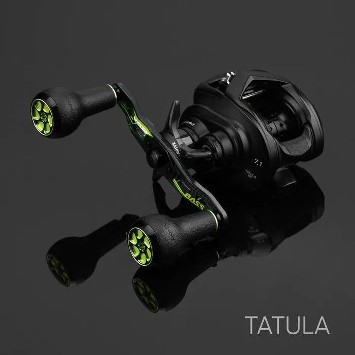 Ein Gomexus Camo Carbon-Griff (95 mm) mit 27 mm TPE-Knöpfen (8 x 5 mm) befindet sich auf einer reflektierenden schwarzen Oberfläche und besticht durch sein ergonomisches Design in Schwarz und Grün. In der unteren rechten Ecke erscheint der Schriftzug TATULA.