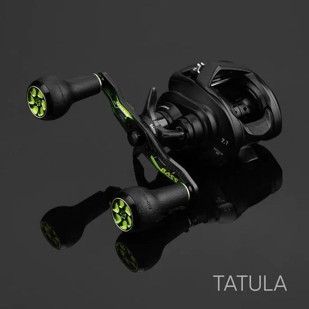 Ein Gomexus Camo Carbon-Griff (95 mm) mit 27 mm TPE-Knöpfen (8 x 5 mm) befindet sich auf einer reflektierenden schwarzen Oberfläche und besticht durch sein ergonomisches Design in Schwarz und Grün. In der unteren rechten Ecke erscheint der Schriftzug TATULA.