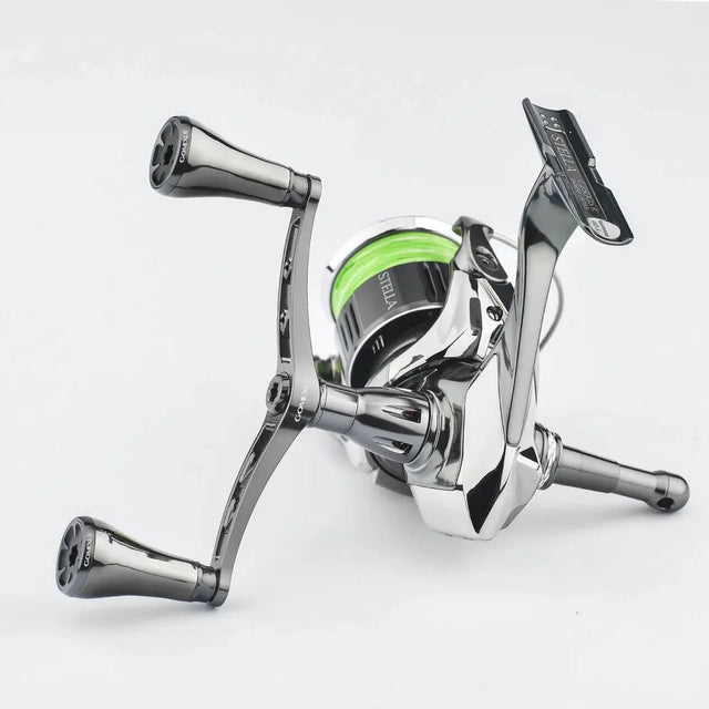 Eine Nahaufnahme der Gomexus-Doppelkurbel 98–82 mm mit T20-Knöpfen für Shimano-Rollen, mit zwei Power-Knöpfen aus Titan und einem Rahmen aus Aluminiumlegierung 7075, mit teilweise aufgespulter grüner Angelschnur, vor einem schlichten weißen Hintergrund.
