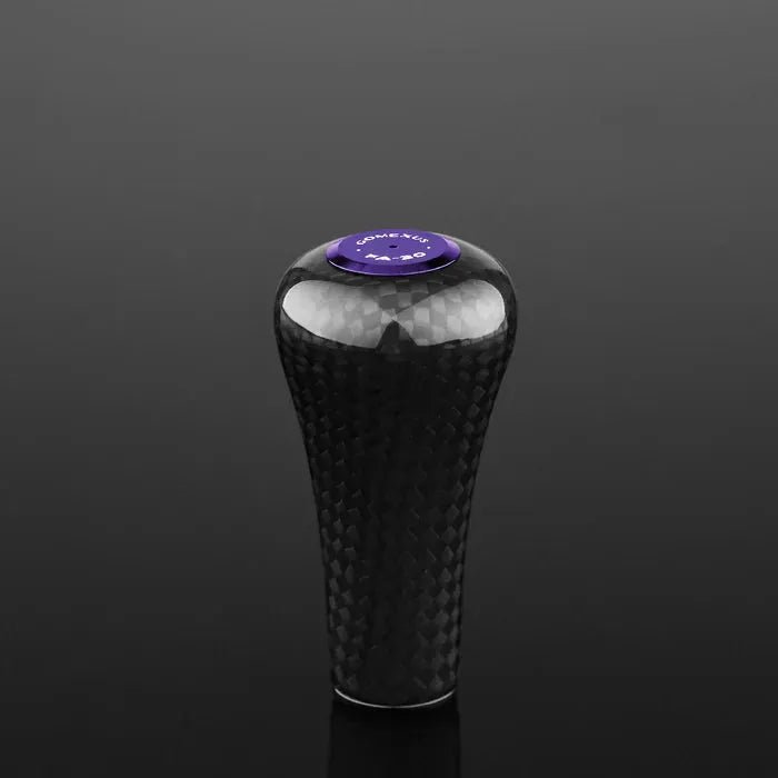 Der Gomexus FA30 Carbon Knob von Gomexus ist ein schwarzer Toray-Carbonfaser-Schaltknauf mit glänzender Oberfläche und einer violetten runden Oberseite mit weißem Text auf einem schwarzen Hintergrund.