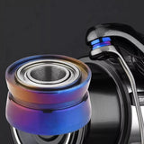 Nahaufnahme eines Gomexus Schnurlaufröllchens für Shimano Angelrollen von Gomexus, mit detaillierten Rillen und Titan-Linienroller-Bügeldraht mit blau-orangem Metallic-Finish vor dunklem Hintergrund.