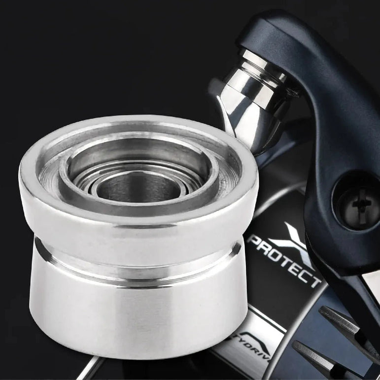 Nahaufnahme eines silbernen Gomexus Schnurlaufröllchens für Shimano SW Angelrollen, vor einer teilweise sichtbaren dunklen Angelrolle mit der Aufschrift „PROTECT“, die den Spulenteil und die detaillierten Gomexus-Rollenkomponenten hervorhebt.