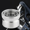 Nahaufnahme eines silbernen Gomexus Schnurlaufröllchens für Shimano SW Angelrollen, vor einer teilweise sichtbaren dunklen Angelrolle mit der Aufschrift „PROTECT“, die den Spulenteil und die detaillierten Gomexus-Rollenkomponenten hervorhebt.