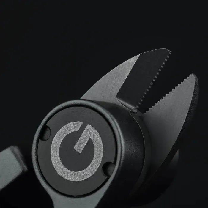 Nahaufnahme der gezackten Backen des Gomexus SharkBite Schnurknipser Combo, mit kreisförmigem Logo mit stilisiertem G auf Schwarz. Edelstahlklingen von Gomexus liefern scharfe, präzise Schnitte.