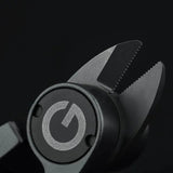 Nahaufnahme der gezackten Backen des Gomexus SharkBite Schnurknipser Combo, mit kreisförmigem Logo mit stilisiertem G auf Schwarz. Edelstahlklingen von Gomexus liefern scharfe, präzise Schnitte.