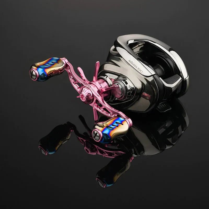 Eine Nahaufnahme der Gomexus Sternbremse 60 mm | Shimano-Rolle von Gomexus mit glänzend schwarzem Gehäuse, rosafarbenem Griff und blau-goldenen Akzenten, dargestellt auf einer reflektierenden schwarzen Oberfläche.