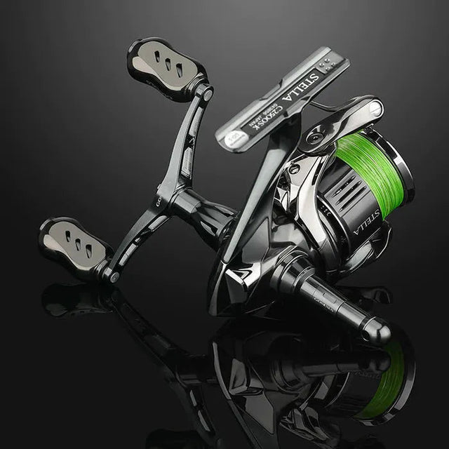 Eine Nahaufnahme einer Shimano Stella-Rolle mit grüner Schnur, aufgerüstet mit einem Gomexus Titanium 22 mm Knob, sitzt auf einer reflektierenden schwarzen Oberfläche.