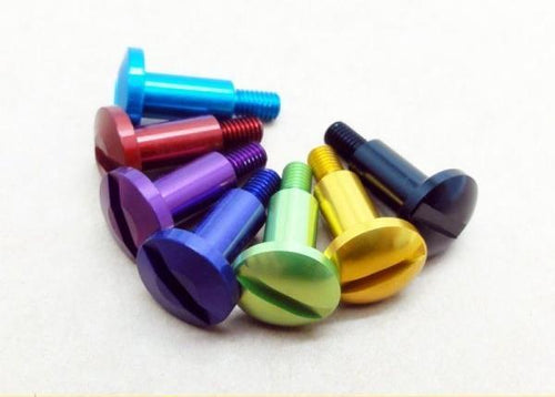 Sieben Hedgehog Studio Daiwa Bremsschraube Bremsscheibenschrauben in Blau, Rot, Lila, Grün, Gelb, Gold und Schwarz aus Duraluminium sind in einer geschwungenen Linie auf einer hellen Oberfläche angeordnet.
