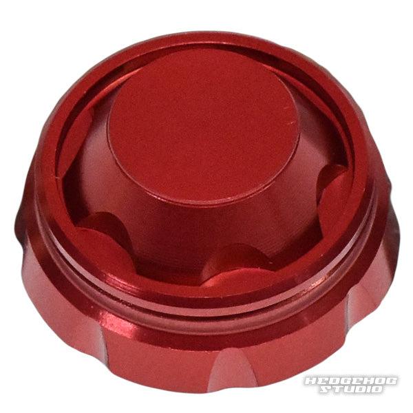 Auf einem weißen Hintergrund ist ein roter, metallischer Hedgehog Studio Handle Screw Cap mit geriffelten Kanten und einer glatten, flachen Oberseite mit einem schwachen HEDGEHOG STUDIO-Wasserzeichen in der unteren rechten Ecke abgebildet.