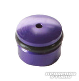 Eine kleine, zylindrische, metallisch-lila Hedgehog Studio-Knopfkappe für Daiwa Finesse-Knöpfe mit einem zentralen Loch oben und einem schwarzen O-Ring ist auf einem weißen Hintergrund mit dem Hedgehog Studio-Logo in der unteren rechten Ecke abgebildet.