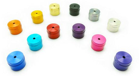 Zwölf Hedgehog Studio Knob Caps für Daiwa I-Shape in Farben wie Blau, Rot, Gold, Silber, Lila und Schwarz sind in einem lockeren Bogen auf weißem Hintergrund angeordnet. Jede Kappe zeigt eine einzigartige Farbe von Hedgehog Studio.