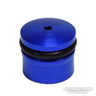 Eine kleine, zylindrische, blaue Duralumin-Knopfkappe von Hedgehog Studio für Daiwa Zaion mit einem Loch oben, einem schwarzen O-Ring in der Mitte und dem Wasserzeichen von Hedgehog Studio unten rechts. Passend für Angelrollen-Zubehör.
