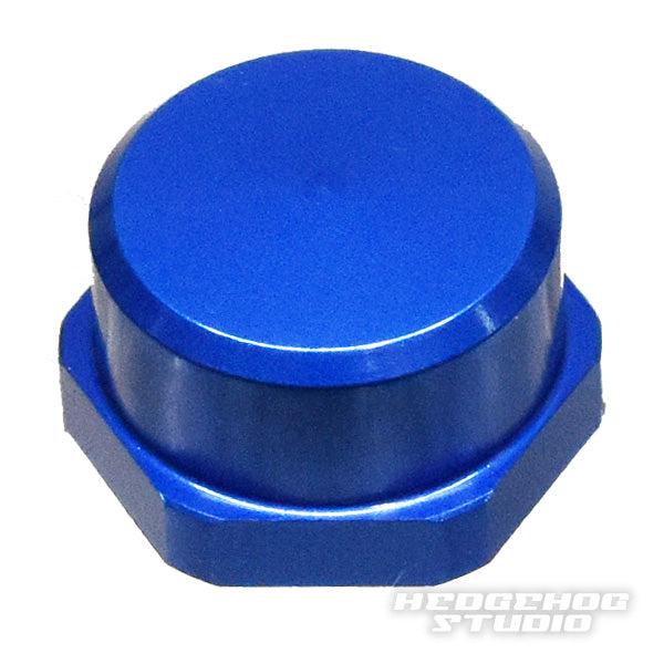 Auf weißem Grund ist eine metallisch blaue Sechskantkappe mit glatter, runder Oberseite abgebildet. Das Hedgehog Studio Logo ist schwach zu erkennen und weist darauf hin, dass es sich um die Shimano Handle Locknut M7 für originale Shimano Kurbeln von Hedgehog Studio handelt.