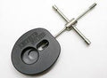 Ein kreuzförmiger Windeisenschlüssel aus Metall, ähnlich dem Hedgehog Studio Spool Bearing Pin Remover Type R, ist an einem schwarzen Adapter mit der Aufschrift KWIKSTER STUDIOS mit kreisförmigen und ovalen Aussparungen befestigt.