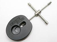 Ein kreuzförmiger Windeisenschlüssel aus Metall, ähnlich dem Hedgehog Studio Spool Bearing Pin Remover Type R, ist an einem schwarzen Adapter mit der Aufschrift KWIKSTER STUDIOS mit kreisförmigen und ovalen Aussparungen befestigt.