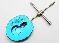 Ein blauer Hedgehog Studio Spool Bearing Pin Remover Type R mit eingraviertem Text und zwei kreisförmigen Vertiefungen befindet sich neben einem silbernen Stiftentferner mit drehbaren Griffen, beide auf weißem Hintergrund.