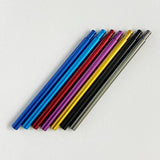 Sieben Metallstifte in verschiedenen Farben sind auf einer weißen Oberfläche aufgereiht - ideal, um Notizen oder Ideen zu notieren, während Sie Ihren Shimano 22 Aldebaran BFS mit dem Level Wind Shaft von Hedgehog Studio stimmen.